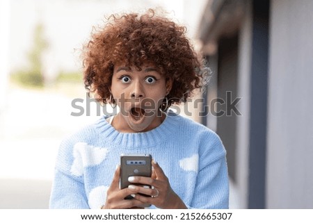 girl in the street with mobile phone and expression of surprise