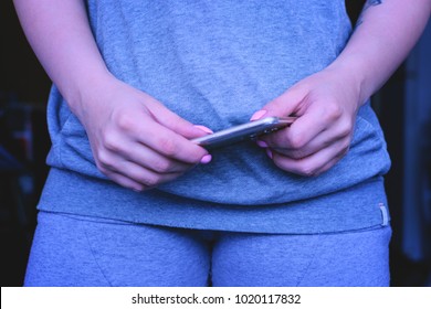 The girl in the striped shirt is typing on a mobile phone. No face. Soft focus. The background substrate - Shutterstock ID 1020117832