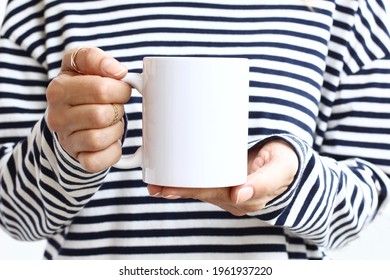 Girl in  striped sweatshirt holding white coffee mug , white porcelain mug mock up. 11 oz mockups
 - Shutterstock ID 1961937220
