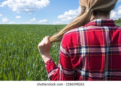 A Girl Strokes Her Braid Against The Background Of A Field Of Corn. Girl Farmer On The Field