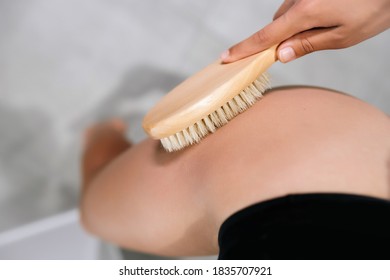 Mädchen streichelt sich das Bein mit einer Bürste im Badezimmer