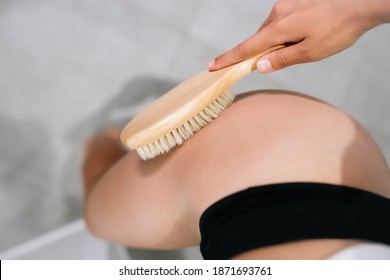 Mädchen streichelt sich das Bein mit einer Bürste im Badezimmer