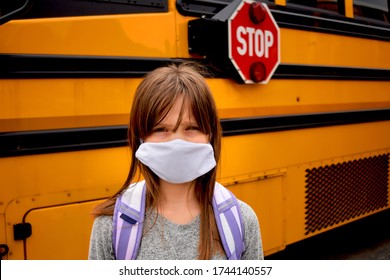 Girl, Student, Child Wearing Face Mask And Standing By A School Bus. For Education, Health, Medical, Safety Concepts Related To Coronavirus, Classrooms, Social Distancing, Back To School Reopening.