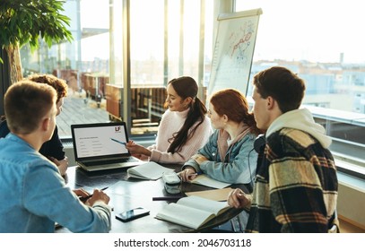 Girl Student Explaining Presentation On Laptop To Classmates In College. Young Female Showing Laptop To Her Friends During Group Study In High School.