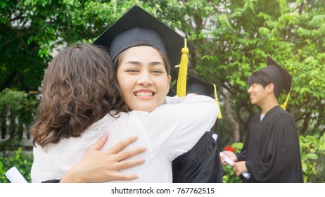 Girl Student With The Graduation Gowns And Hat Hug The Parent In Congratulation Ceremony.
