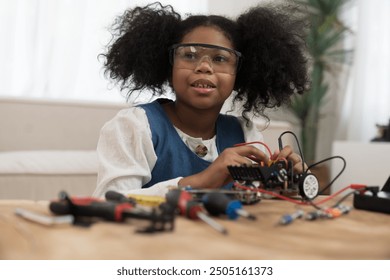 Girl student learning and building project toy robotics technology at home. African American child girl training and control toy robot in classroom