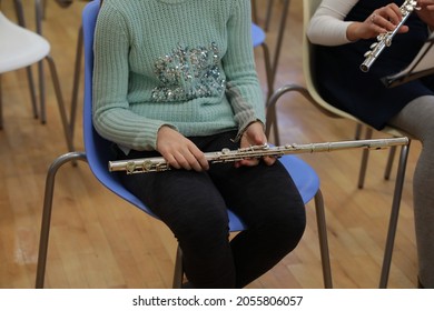 Girl student with a musical instrument flute sitting in the hall at the rehearsal of the school orchestra.Child hobby leisure learning music background image in informal clothes free pose close-up - Powered by Shutterstock