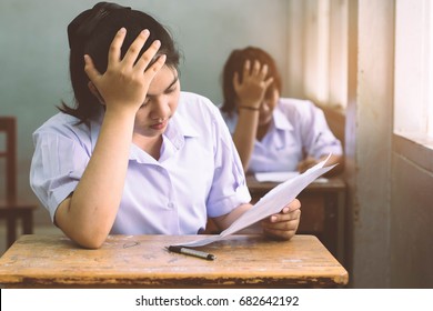 Girl Student Reading And Writing Exam With Stress.