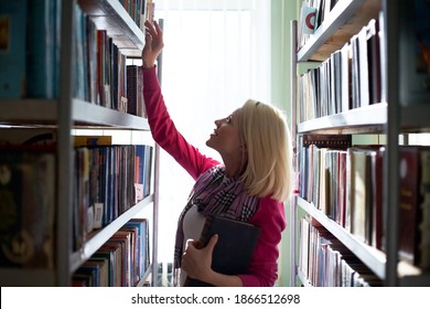 Girl student selects a book at the library - Shutterstock ID 1866512698