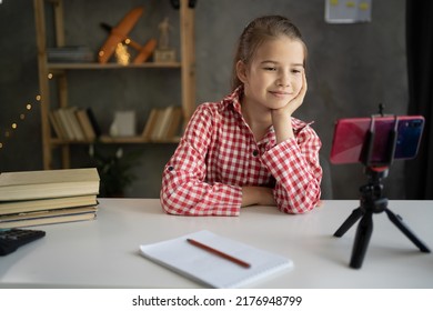 Girl Student Studying Online At Home, Looking At Phone Screen, Watching Webinar, Using Smartphone On Tripod, Writing Notes, Homeschooling Concept