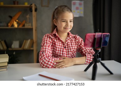 Girl Student Studying Online At Home, Looking At Phone Screen, Recording Video Talking To Cellphone On Tripod, Watching Webinar, Using Smartphone On Tripod, Writing Notes, Homeschooling Concept