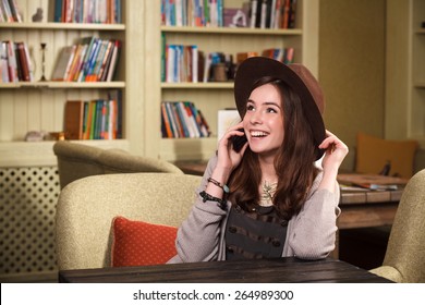 girl student talking on the phone in a cafe, university. Young woman talking on the phone in a cafe - Powered by Shutterstock