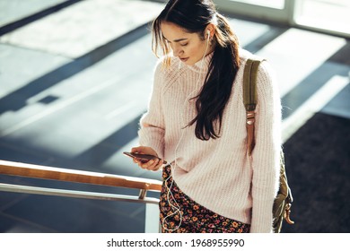 Girl Student Using Mobile And Going Upstairs In High School Campus. Young Woman Checking Her Social Media Status Before Going For Class.