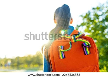 girl student wears backpack outdoors in summer park