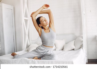 Girl in a studio. Lady in a gray sportsuit. Woman making a yoga.