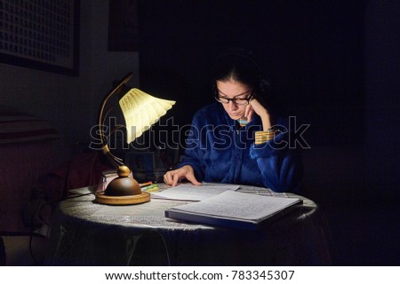 girl studying illuminated by a lamp