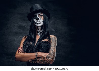 A girl in stylish top hat with skull make up and tattoo on arm. Halloween party.