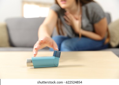 Girl suffering asthma attack reaching inhaler sitting on a couch in the living room at home - Shutterstock ID 622524854