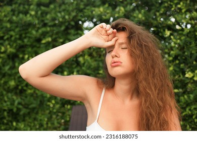 Girl is suffering from heat, woman with heatstroke. Having sunstroke at summer hot weather. Dangerous sun, girl under sunshine. Headache. Person holds hand on head. Feeling bad, unwell, unhealthy