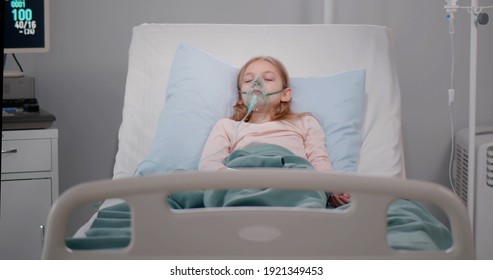 Girl suffering from pneumonia lying in a hospital bed with oxygen mask. Preteen kid patient with asphyxia breathing in oxygen mask sleeping in bed at ward - Powered by Shutterstock