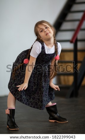 
Girl in a sundress grimaces on the background of the stairs