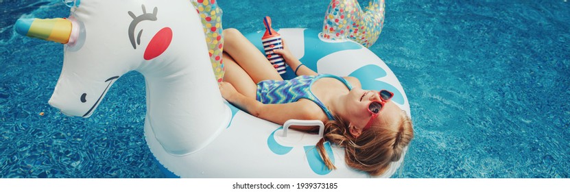 Girl In Sunglasses With Drink Lying On Inflatable Ring Unicorn. Kid Child Enjoying Having Fun Relaxing In Swimming Pool On Floatie. Summer Outdoors Water Activity For Kids. Web Banner Header.