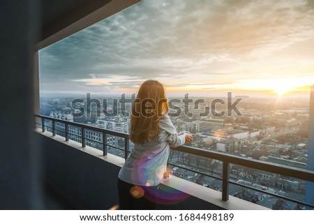 girl at sunset looks at the city. Girl on the balcony against the background of the urban city