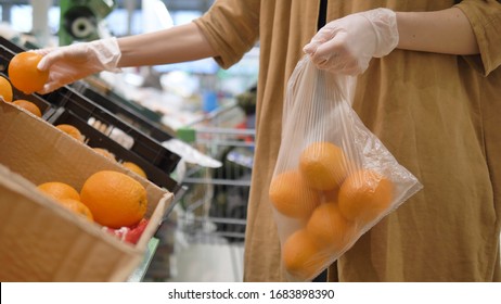 A Girl In A Supermarket Selects Fresh Oranges In Rubber Gloves And Puts Them In A Plastic Bag. Healthy Nutrition To Increase Immunity. Protective Measures Against The Coronavirus Pandemic.