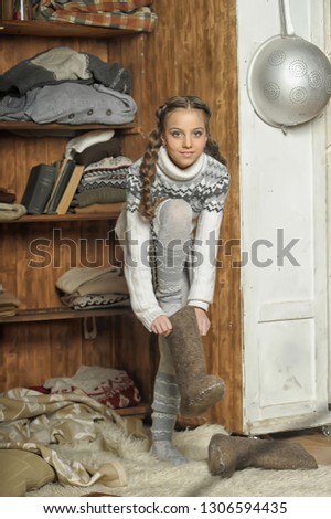 girl in a sweater and boots at the wardrobe with warm clothes