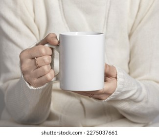 Girl in a sweater holding white coffee mug 11 oz, white porcelain mug mock up - Shutterstock ID 2275037661