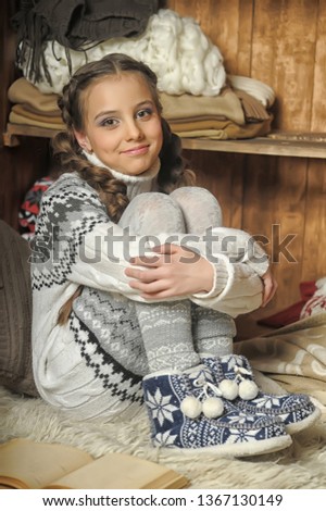 girl in a sweater puts warm sneakers in cold weather at home