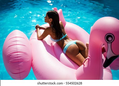 girl in swimming pool on inflatable flamingo