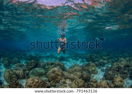 Girl swimming in the sea above beautiful corals in lagoon in Thailand