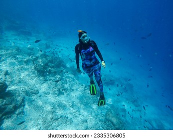 Una niña con traje de baño y aletas se dedica al submarinismo libre sin equipo de buceo en aguas profundas cerca del gran arrecife