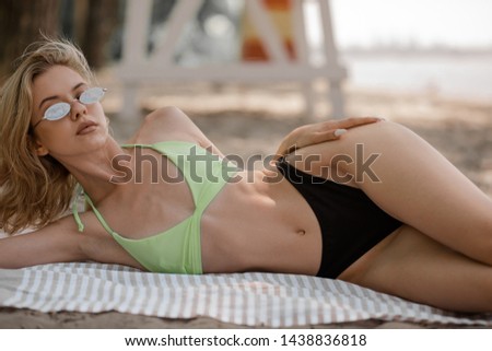 Girl in a swimsuit lying on a blanket on the beach. Devushka glasses on the beach