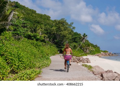 A Girl In A Swimsuit On The Bike On La Digue. Tropical Seychelles