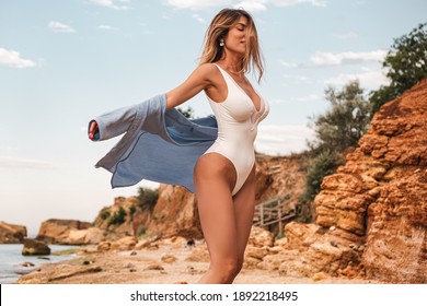 Girl in swimwear posing at the beach, Tanned young woman in swimsuit posing in sea water among rocks, blonde girl at the beach, body, attractive, pretty, make up, model, hairstyle, nails, shirt, curly