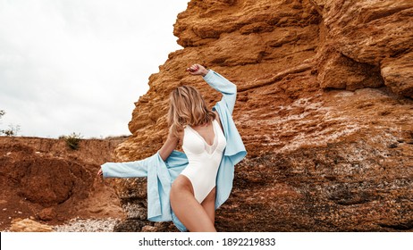 Girl in swimwear posing at the beach, Tanned young woman in swimsuit posing in sea water among rocks, blonde girl at the beach, body, attractive, pretty, make up, model, hairstyle, nails, shirt, curly