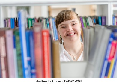 Mädchen mit Syndrom wählt ein Buch in einem Regal in der Bibliothek. Konzept "Bildung für behinderte Kinder"