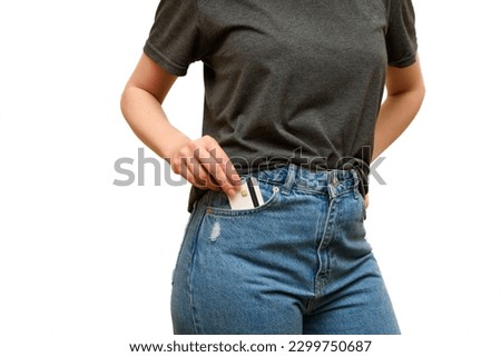 Girl take credit card from pocket jeans pants. Woman's is wearing blue jeans and gray t-shirt. Casual wear. Shopping trip. Payment for purchases by credit card. 