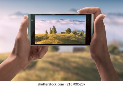 Girl Take A Picture Of Alpine Village In A Mountain Valley On Her Smartphone. Travel Concept.