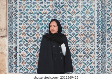 A girl is take a pose in front of the Mosaic Pattern Wall in the Topkapi building