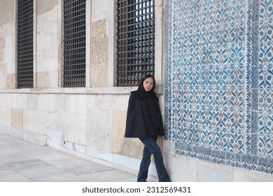 A girl is take a pose in front of the Mosaic Pattern Wall in the Topkapi building