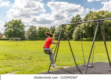 A Girl Takes A Momentum On A Swing In A Playground On A Beautiful Sunny Day