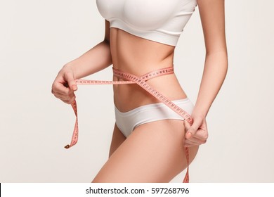 The girl taking measurements of her body, white background.