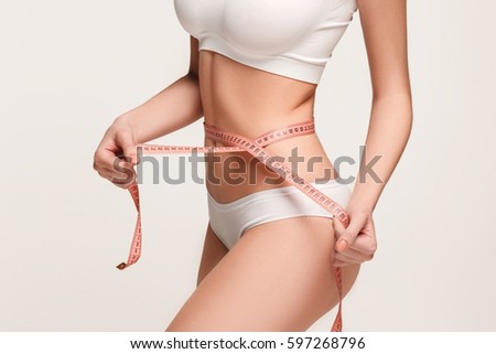 The girl taking measurements of her body, white background.