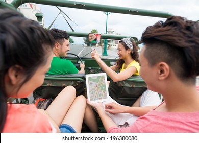 Girl Taking A Picture Of The Car Driver While Her Friends On The Backseat Are Using Tablet With Navigator On The Screen