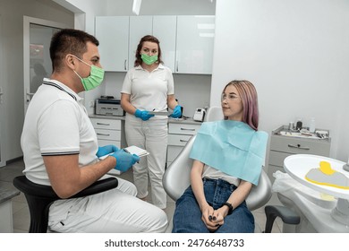 girl talking consulting with Caucasian male dentist and assistant. young woman feels happy to receive care from a professional dentist for tooth decay  gum disease in a dental care program.dentistry - Powered by Shutterstock