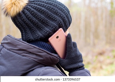 Girl Talking On A Cell Phone. Woman Communicates On The Cellular In Warm Winter Gloves.holding A Mobile Phone Near The Ear