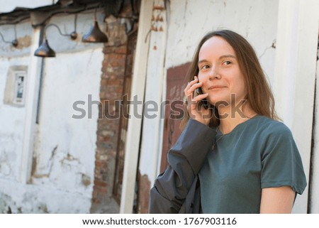 The girl is talking on the phone. Smiling while talking on a smartphone. Positive conversation, communication with friends. Outdoor